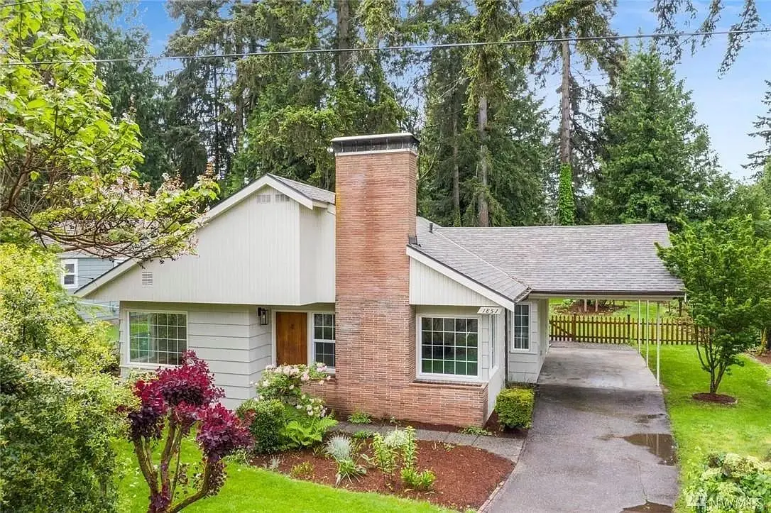 A house with a driveway and trees in the background