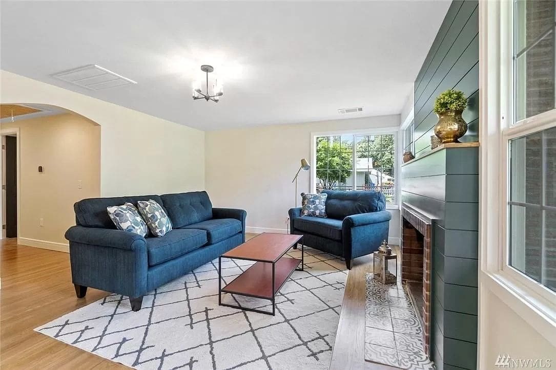 A living room with blue couches and a fireplace.