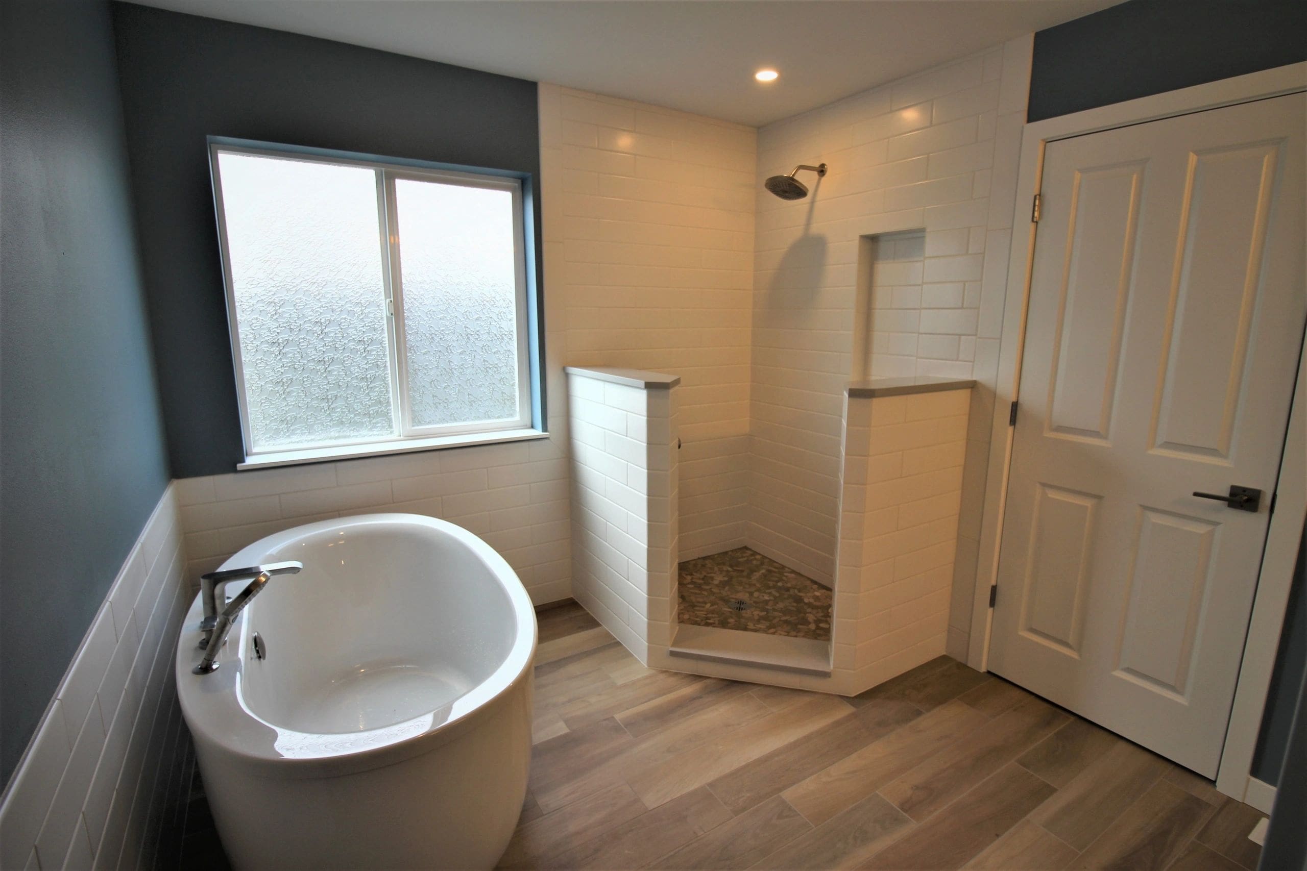 A bathroom with a tub, shower and window.