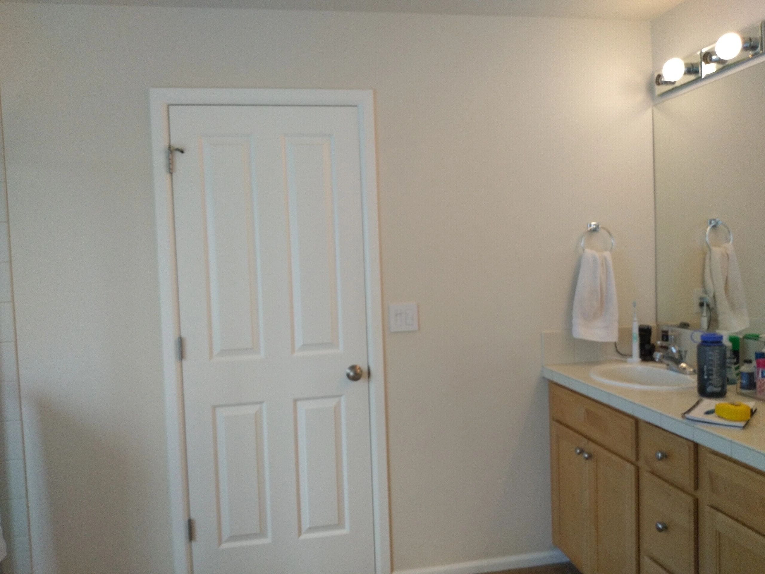 A bathroom with white walls and wooden cabinets.