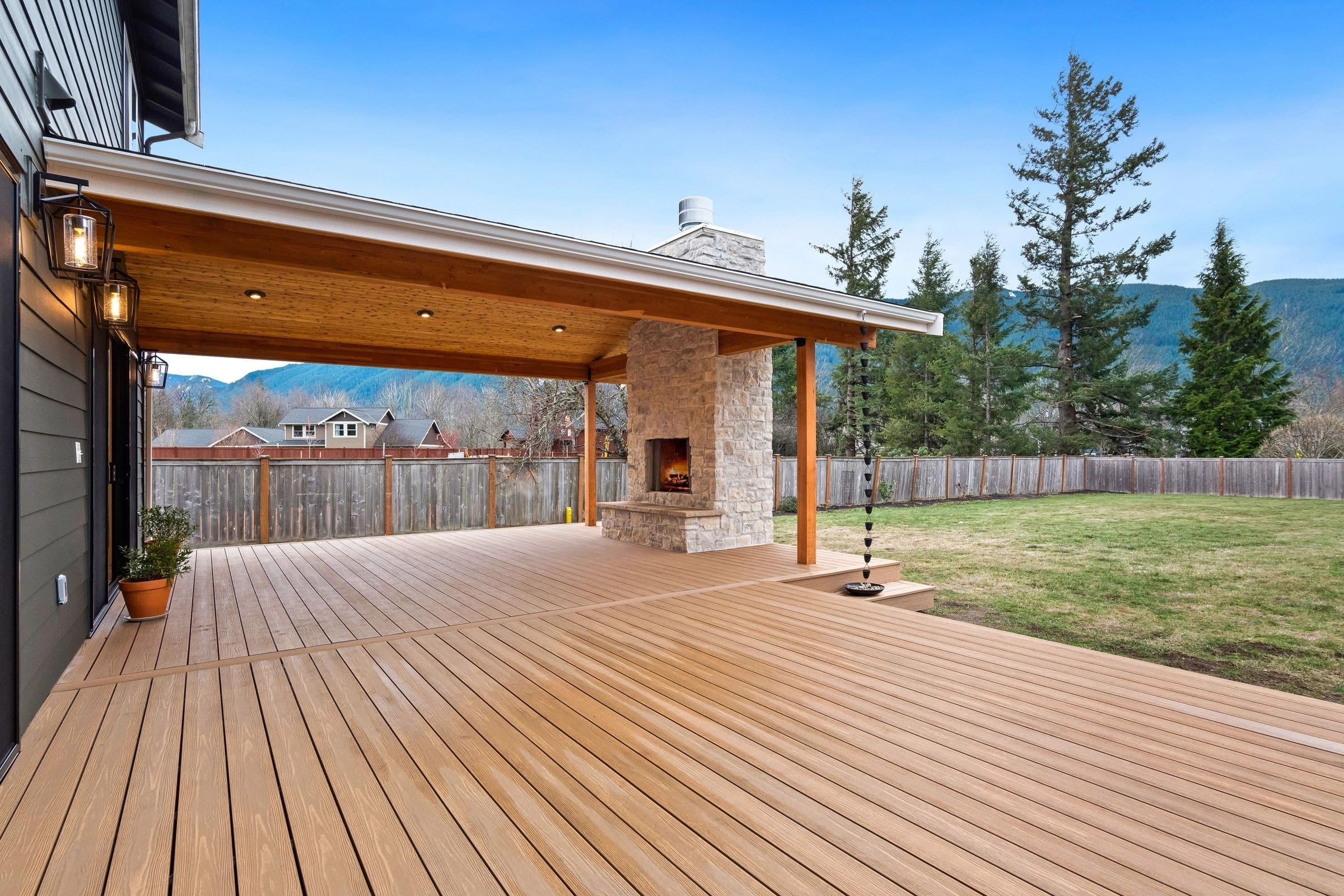 A large wooden deck with a fireplace and a fire pit.