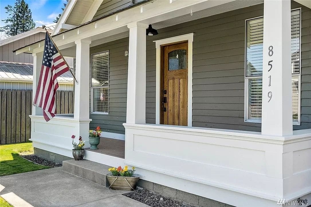 A house with an american flag hanging on the front porch.