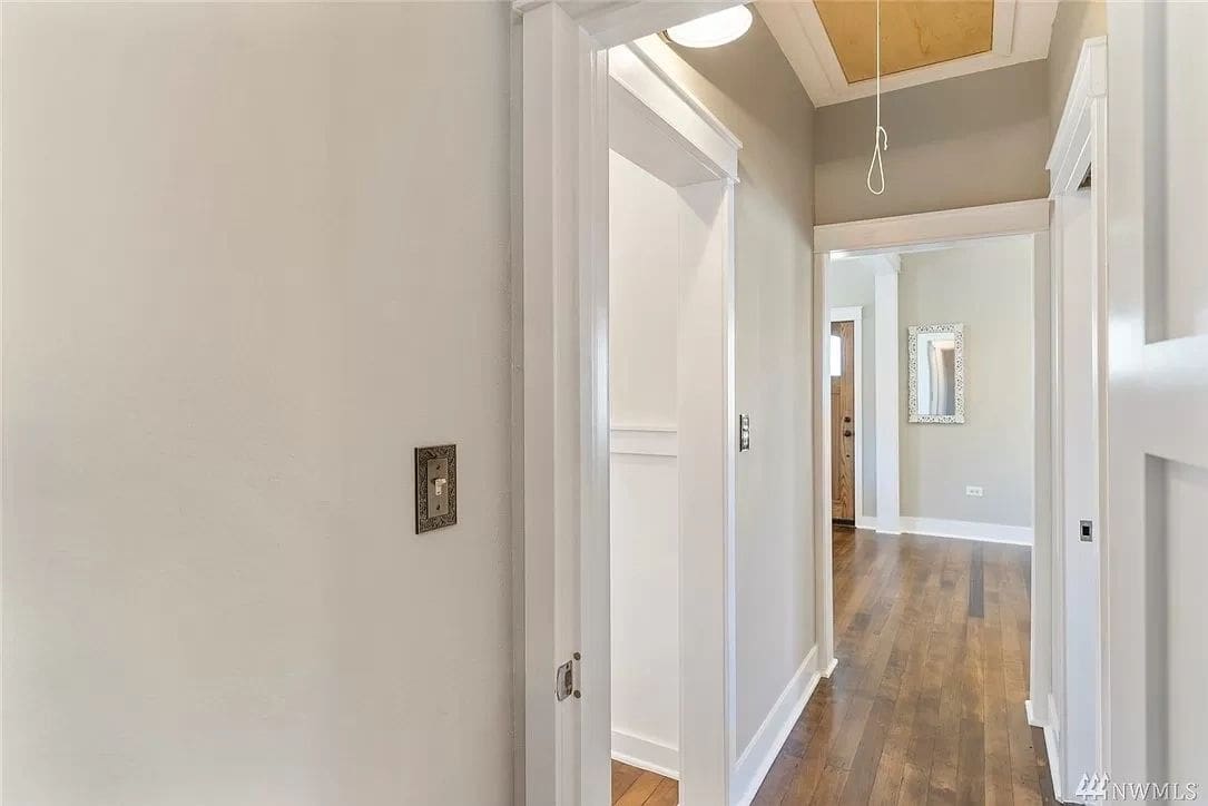 A hallway with white walls and wooden floors.