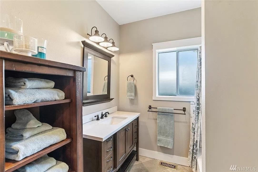 A bathroom with a sink, mirror and towel rack.