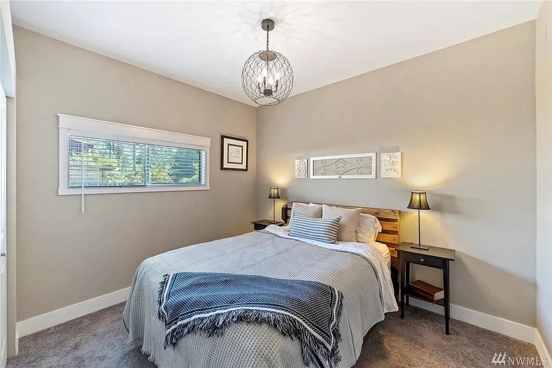 A bedroom with a bed, nightstand and window.