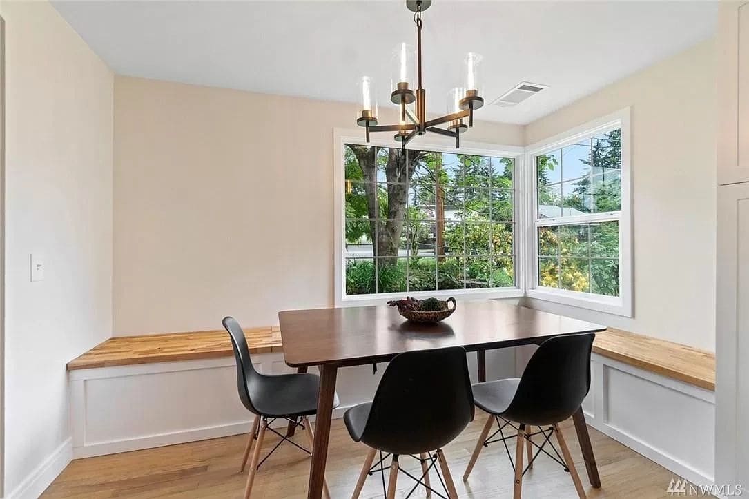 A dining room table with chairs and a bench in the corner.