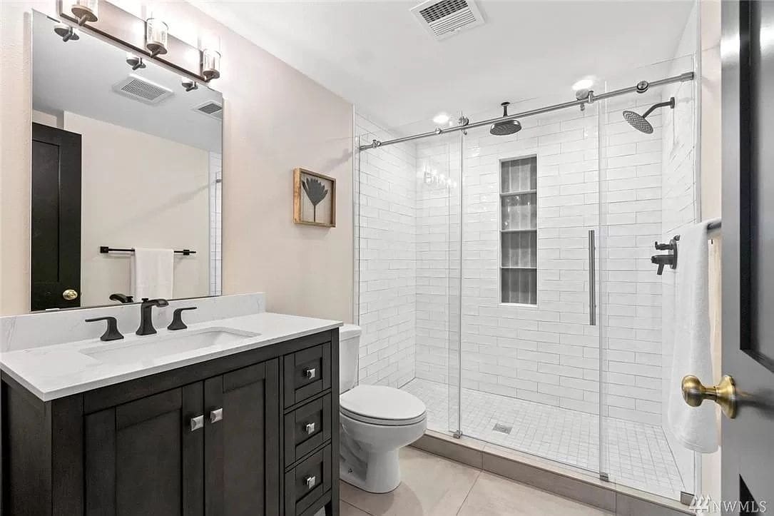 A bathroom with a toilet, sink and shower.