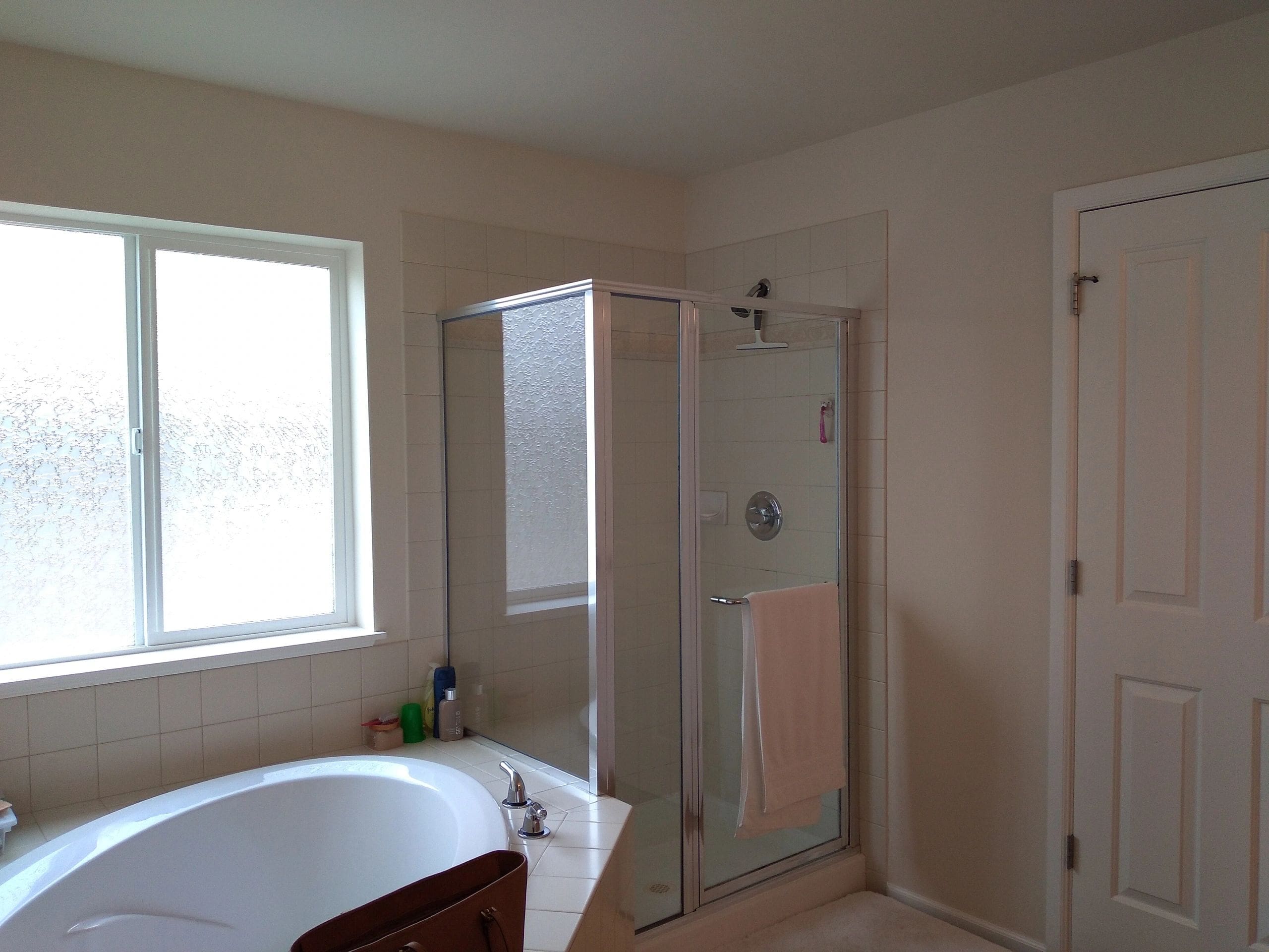 A bathroom with a tub, shower and window.