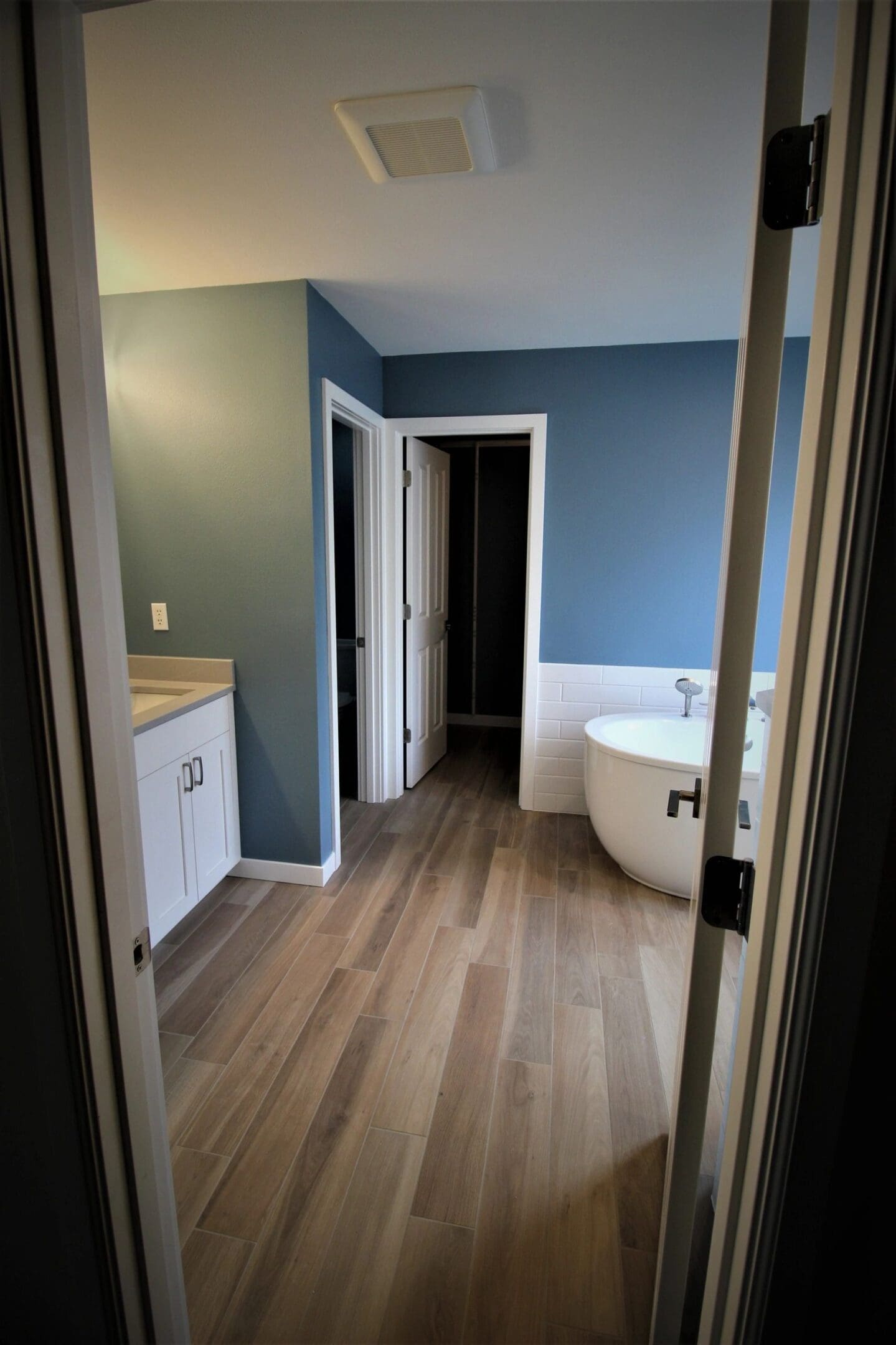 A bathroom with blue walls and white cabinets.