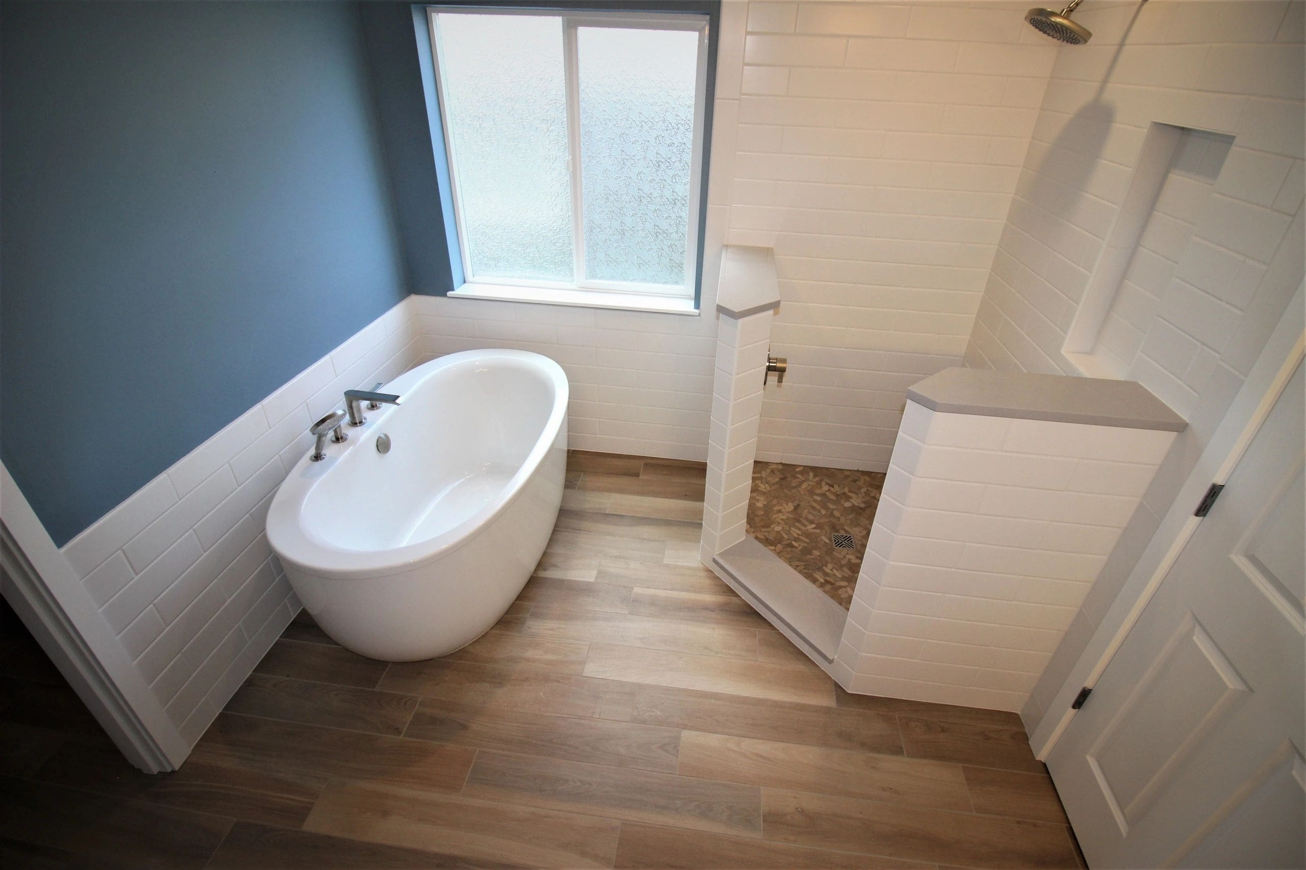 A bathroom with wood floors and white fixtures.