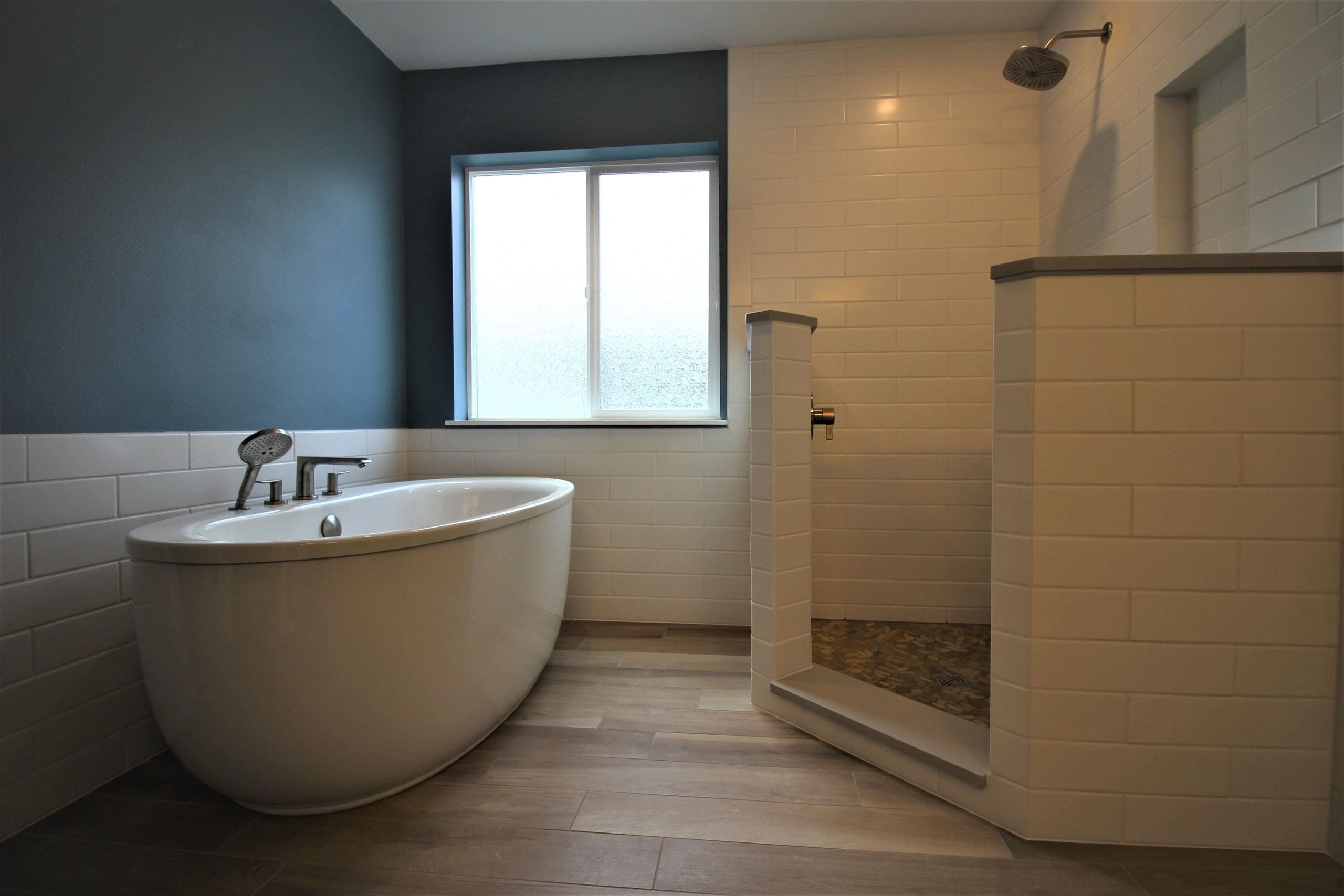 A bathroom with a tub, shower and window.