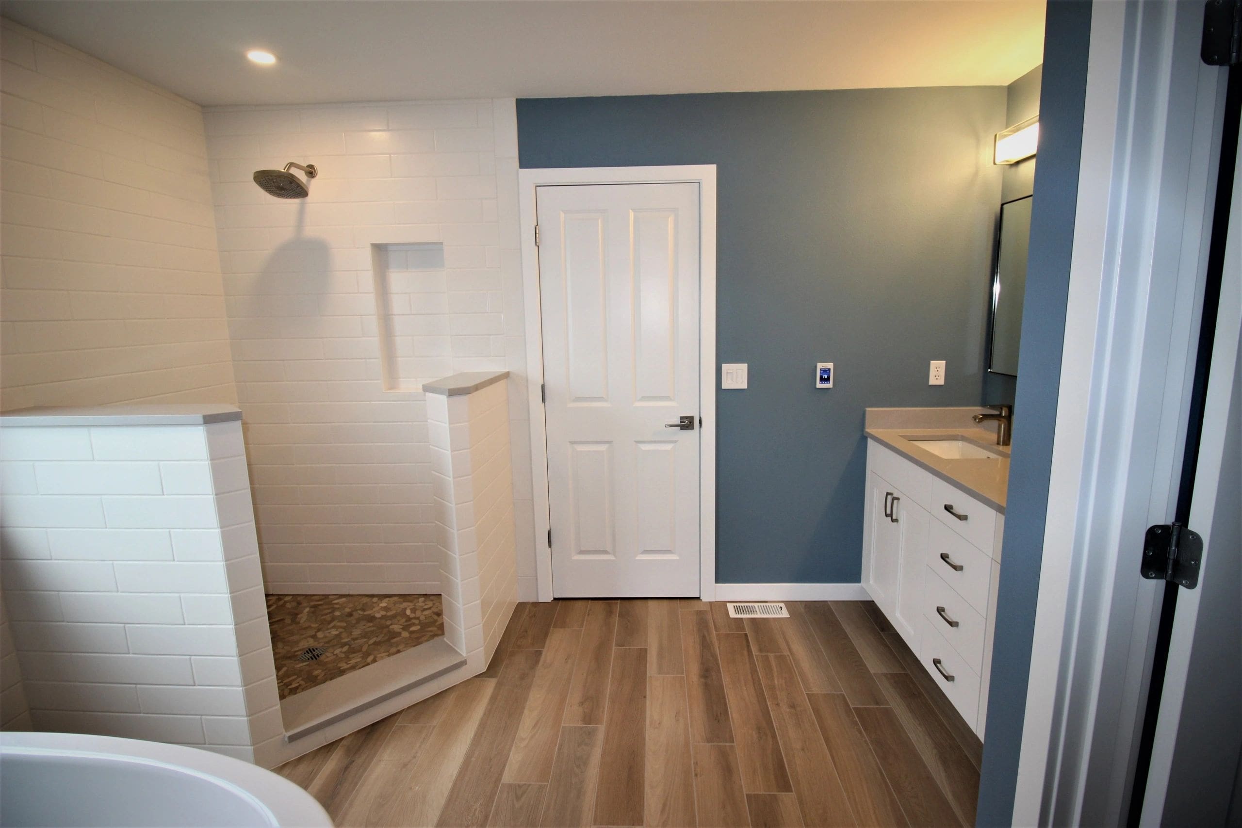 A bathroom with wood floors and blue walls.