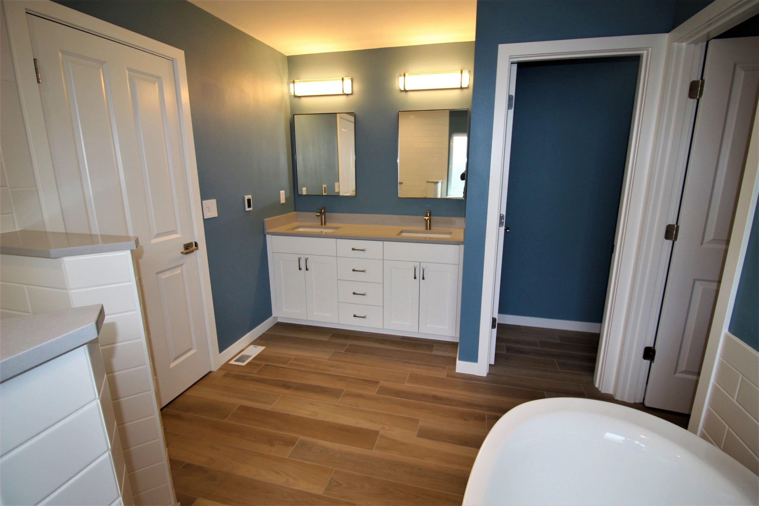 A bathroom with blue walls and white cabinets.