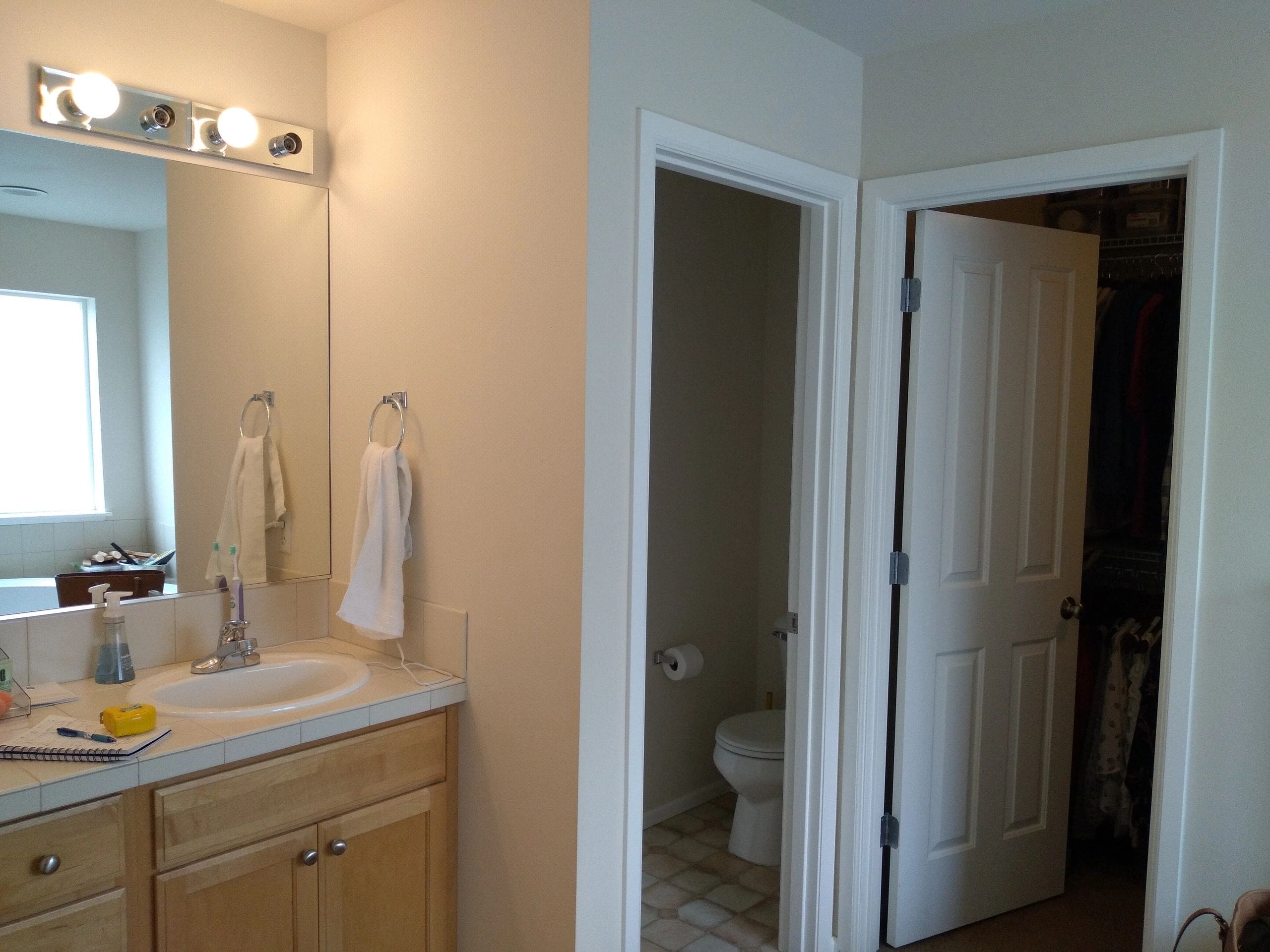 A bathroom with a sink, toilet and mirror.